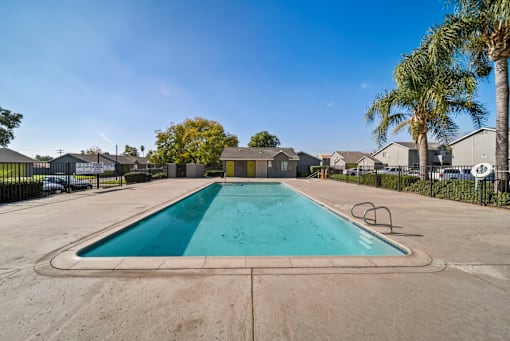 A swimming pool surrounded by a fence and palm trees.