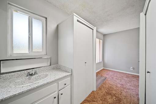 A bathroom with a sink, mirror, and a carpeted floor.