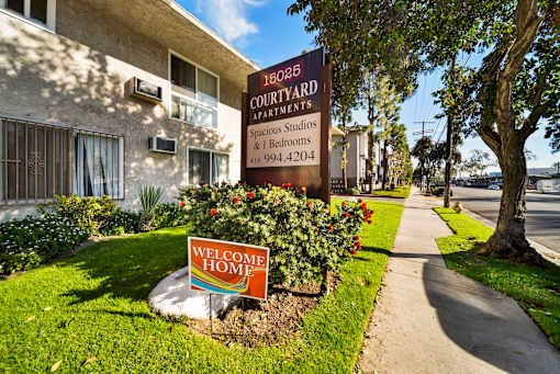 A sign for 16025 Courtyard Apartments is displayed in front of a building.