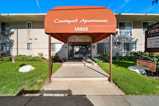 The entrance to Courtyard Apartments with a red sign on the right.