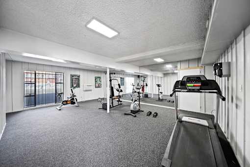 A gym with a treadmill, exercise bike, and other equipment.