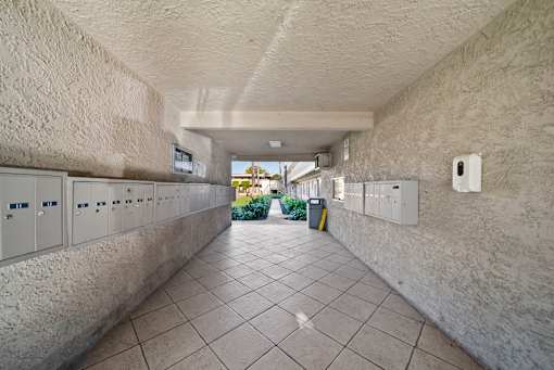 A long hallway with a row of lockers on the left and electrical boxes on the wall.
