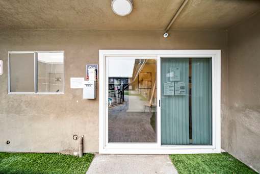 A white door with a glass window is open to a backyard.