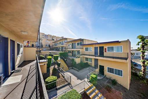 A sunny day at a residential complex with apartments and greenery.
