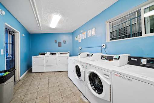 A row of white front load washing machines in a laundromat.