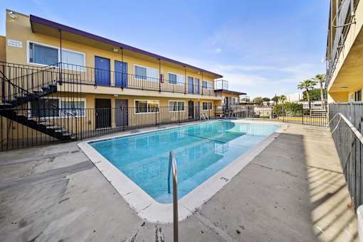 A swimming pool is surrounded by a concrete floor and a black fence.