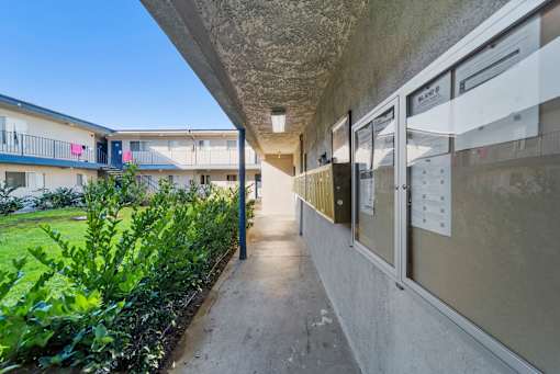 A long concrete walkway leads to a building with a balcony.