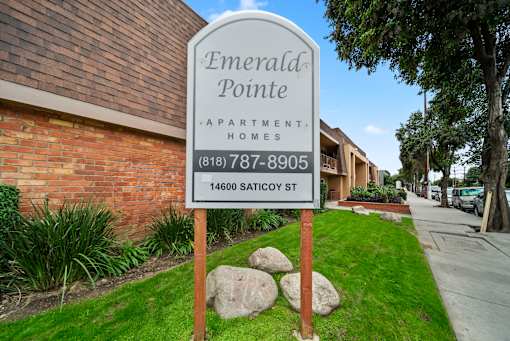 A sign for Emerald Pointe Apartment Homes stands in front of a brick building.