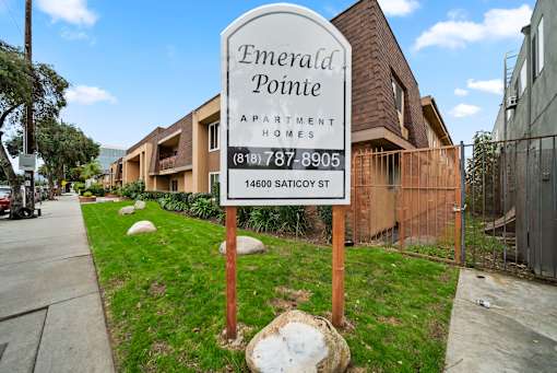A sign for Emerald Pointe Apartment Homes stands in front of a building.