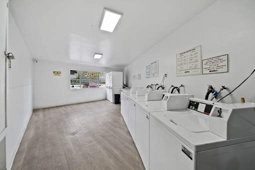 A clean, white-walled laundromat with multiple washing machines.