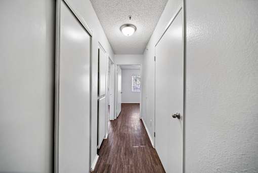 A long hallway with white walls and wood floors.
