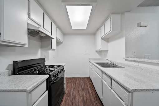 A kitchen with a black stove top oven and white cabinets.