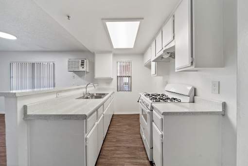 A white kitchen with a stove top oven and a sink.