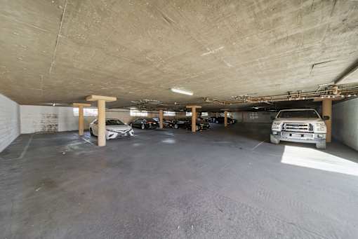 A parking garage with a white car and a brown truck.