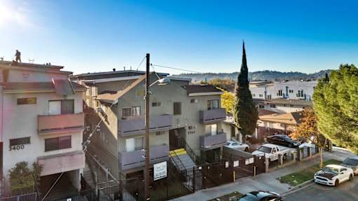 A sunny day in a residential area with cars parked on the street.