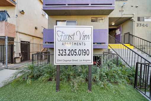 A sign for Forest View Apartments is in front of a building.