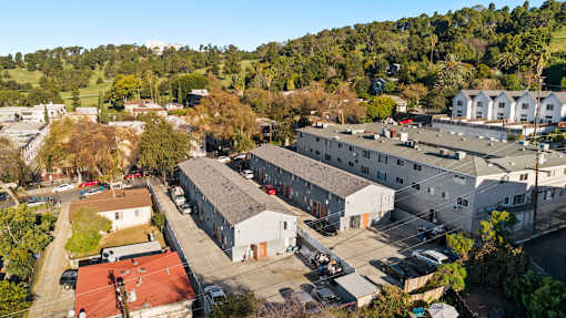 A large white building with a red roof is surrounded by other buildings and trees.