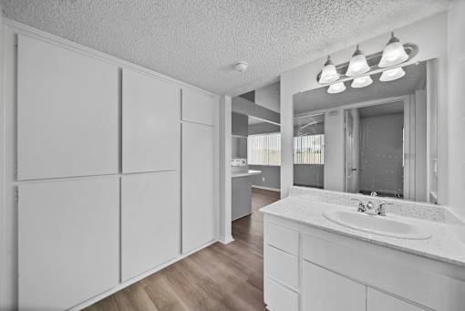 A bathroom with a sink, mirror, and cabinets.