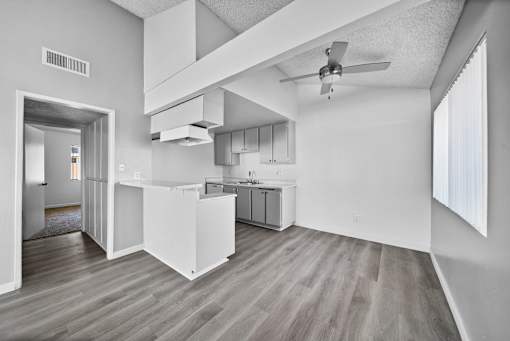 A modern kitchen with a ceiling fan and wooden flooring.