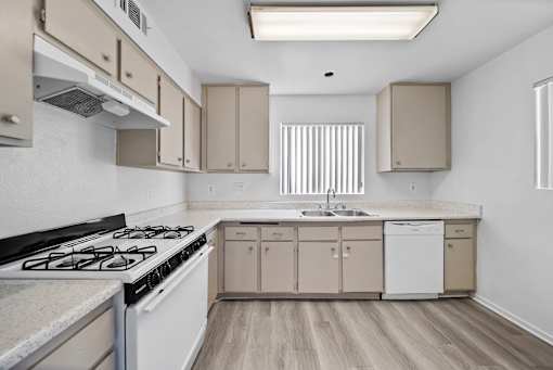 A kitchen with a stove, sink, and cabinets.