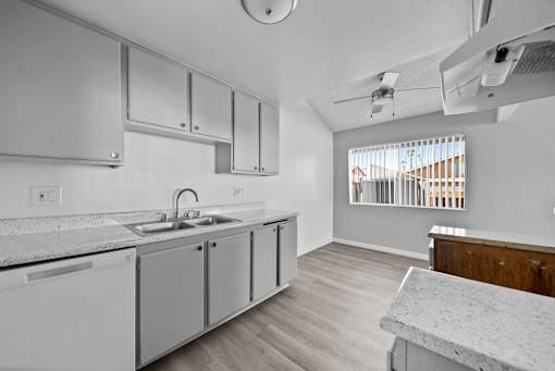 A kitchen with white cabinets and a marble countertop.