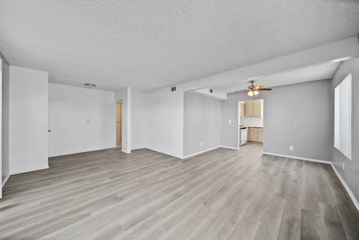A spacious room with wood flooring and white walls.
