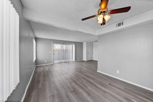 A room with a ceiling fan and sliding glass doors.
