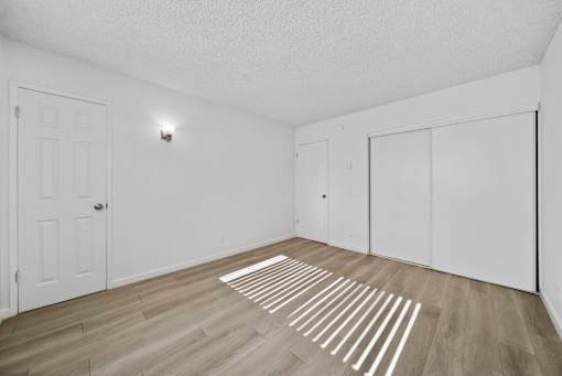 A room with a white door and a white wall with a light switch.