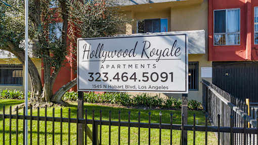 A sign for Hollywood Royale Apartments stands in front of a building.