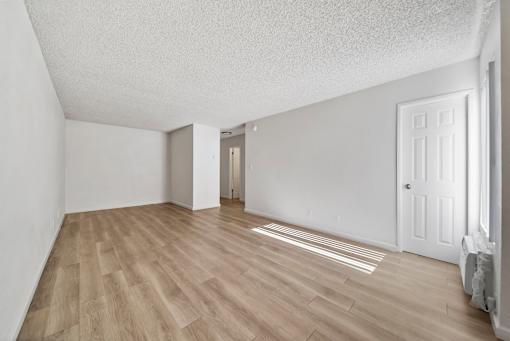 A room with light wood flooring and white walls.