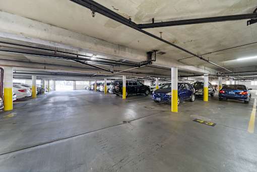 A parking garage with cars parked and yellow poles.