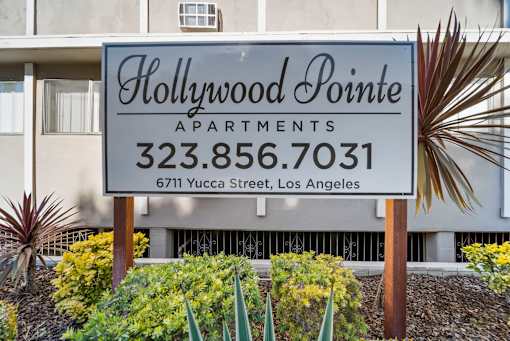 A sign for Hollywood Pointe Apartments stands in front of a building.