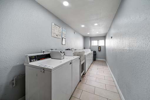 A clean, white-walled industrial kitchen with a row of white ovens and a white countertop.