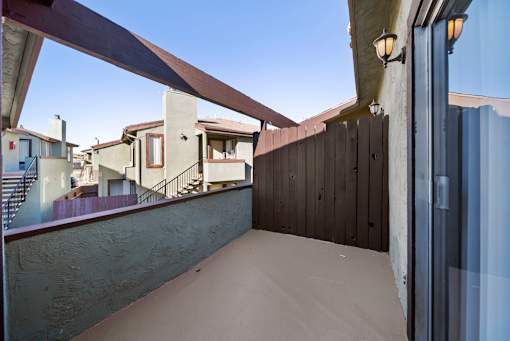 A balcony with a brown railing and a glass door.