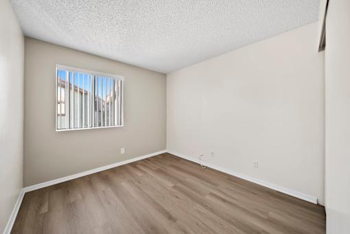 A room with a window and wooden flooring.