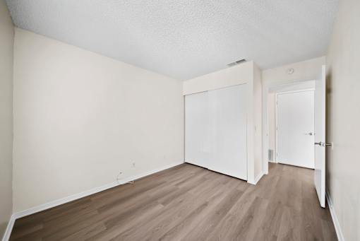 A room with white walls and wooden flooring with a door on the right.