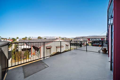A balcony with a black railing and a concrete floor.