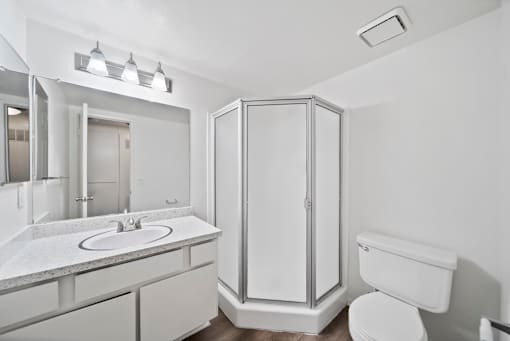 A white bathroom with a sink, toilet, and shower.