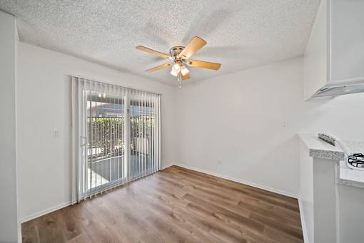 A room with a ceiling fan and sliding glass doors.