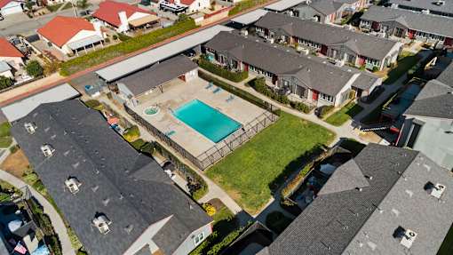 A bird's eye view of a residential area with houses and a swimming pool.