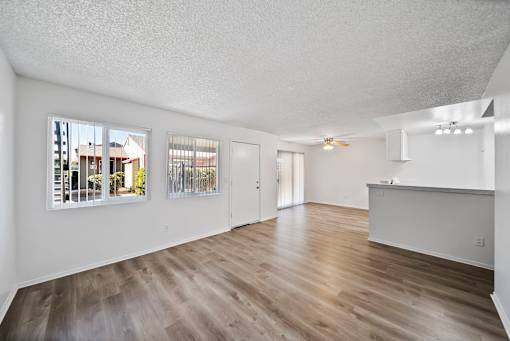 A spacious room with wood flooring and white walls.