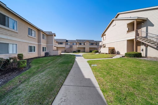 A residential area with apartment buildings and a sidewalk.