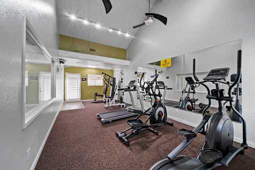 A gym with a variety of exercise equipment including treadmills, stationary bikes, and weight machines.
