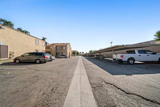 A street with cars parked on the side and buildings in the background.