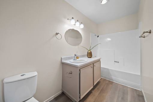 A bathroom with a toilet, sink, and mirror.