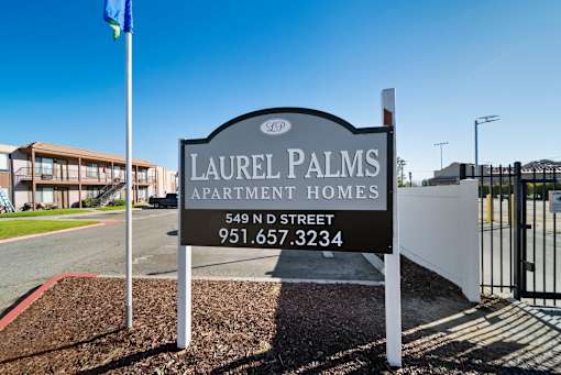 A sign for Laurel Palms Apartment Homes stands in front of a building.