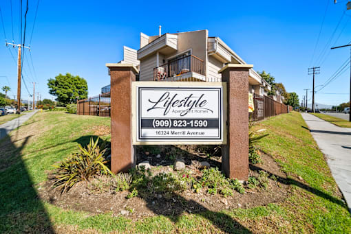 A sign for Lifestyle Apartments with a phone number and address.