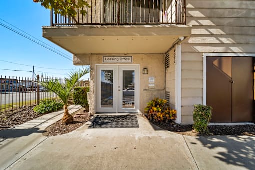 The image shows the front of a building with a leasing office sign on it.