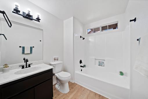 A white bathroom with a toilet, sink, and shower.
