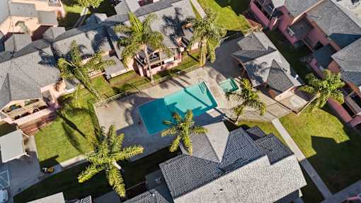 A bird's eye view of a neighborhood with a pool and palm trees.